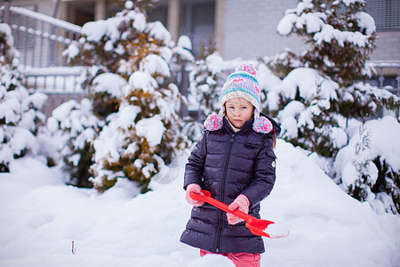 可爱的小女孩在冬日玩雪铲雪游戏雪堆公园快乐微笑幸福季节手套森林晴天孩子图片