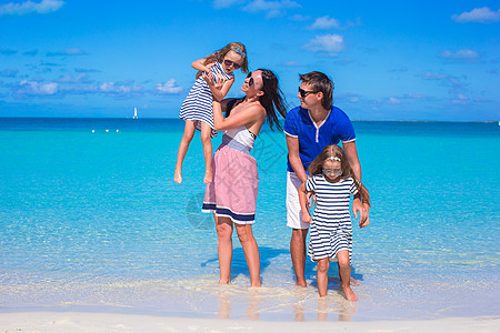 热带白沙滩上四口四口的年轻家庭海洋阳光父母喜悦幸福女儿女孩孩子海岸线海滩图片