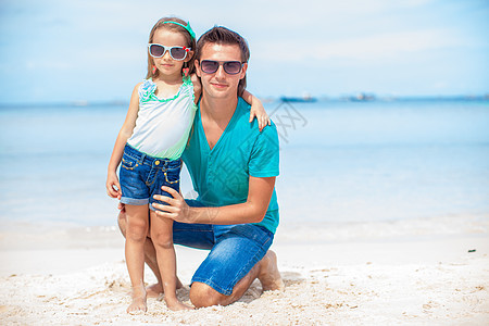 坐在热带白沙滩上的爸爸和女孩父亲异国幸福女士情调孩子男人女性婴儿海岸图片
