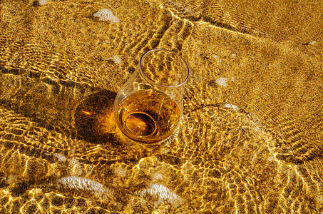 一杯威士忌单麦芽酒 在沙子上被海浪冲洗沿海烈酒麦芽沙滩天气玻璃海岸线活力饮料泡沫图片