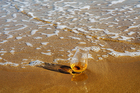 一杯威士忌单麦芽酒 在沙子上被海浪冲洗泡沫沿海海景活力运动饮料麦芽海洋海岸线玻璃图片