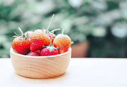 在绿色自然背景的木碗中特写红色草莓食物木头水果浆果叶子图片