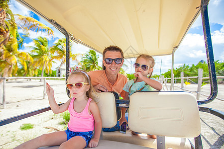 爸爸和他的女儿们 在热带海滩驾驶高尔夫车姐妹大车海岸线运输天空孩子女孩娱乐女儿地平线图片
