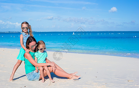 妈妈和两个小女孩在沙滩度假时成人假期海洋父母裙子享受婴儿女性情调女士图片