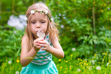 可爱的小女孩 在花园里吹着花棚孩子脸颊行动游戏森林喜悦花朵童年编织手臂图片