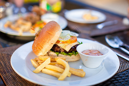室外咖啡厅餐桌上有薯条的经典汉堡汉堡餐厅垃圾面包餐具生活午餐芝士熏肉馒头咖啡店图片