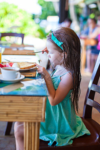 可爱的小女孩在户外咖啡厅吃早餐热带食物蜂蜜西瓜柠檬快乐餐厅金发假期婴儿图片