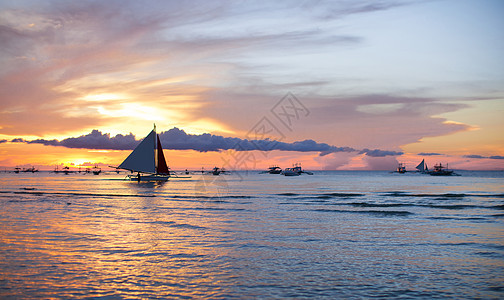 在美丽多彩的夕阳下航行日落活动血管海浪游客地平线海洋游艇海景海岸图片