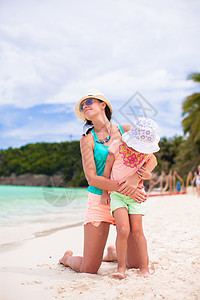 暑假沙滩度假时的小女孩和快乐妈妈父母婴儿海洋母亲女士女儿女性热带帽子情调图片