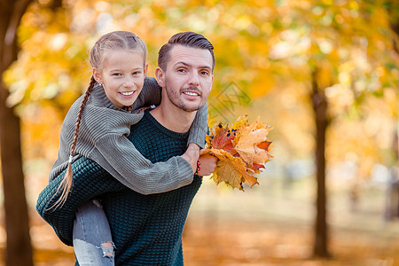 父亲和孩子的家庭 在美丽的秋天在公园里季节树叶婴儿父母女儿男人晴天幸福爸爸金子图片