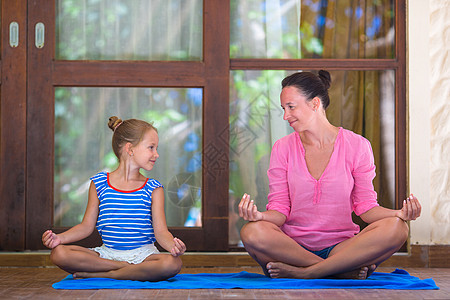 在露台露天做瑜伽锻炼的年轻女性和小女孩身体父母平衡女孩童年姿势幸福成人运动家庭图片