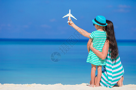 在海滩上拥有小型飞机的年轻女子和小女孩 女孩和少女空气家庭孩子航班假期天空手工喷射工艺行动图片