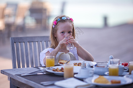 可爱的小女孩在户外咖啡厅吃早餐咖啡店金发杯子蜂蜜孩子快乐食物餐厅假期眼睛图片