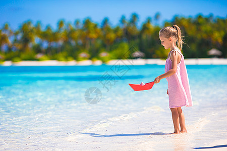 可爱的小女孩在松绿海玩折纸船上游戏海洋导航玩具孩子航行裙子自由旅行环境假期图片