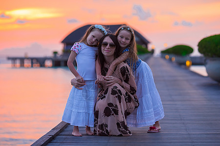 日落时 年轻母亲和两个小女孩的休眠海岸线享受女士家庭假期婴儿海岸帽子孩子女儿图片