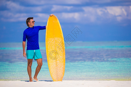 年轻冲浪手在白沙滩上快乐 带着黄色冲浪板热带木板运动游泳衣蓝色支撑冲浪旅行假期跑步图片