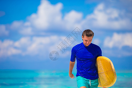 年轻冲浪手在白沙滩上快乐 带着黄色冲浪板旅游男人游泳木板闲暇男性海岸阳光冲浪者海洋图片