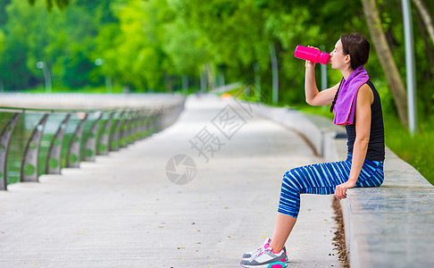 拥有户外水垫和水瓶的年轻活跃健身女青年微笑肌肉运动装运动员活动女孩腹部训练腹肌公园图片