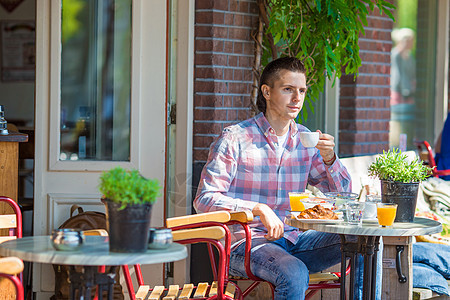 快乐的年轻人坐在室外咖啡厅里 在欧佩安市喝咖啡图片