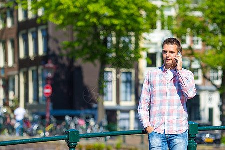 欧洲城市桥上用手机聊天的 年轻天主教徒男子技术闲暇消息照片游客漫游自行车运输男生小路图片