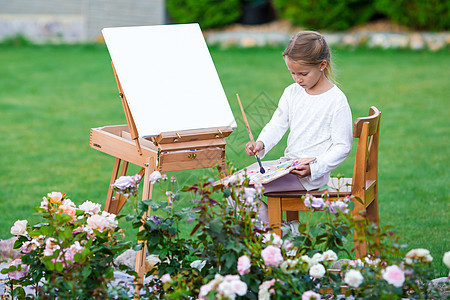 可爱的小女孩在户外温暖的一天 在壁架上画一幅图片婴儿艺术孩子木板绘画职业童年画架紫色草稿图片