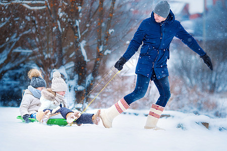 享受雪橇的小女孩 父亲带着他可爱的小女儿们滑雪橇 在户外圣诞前夜的家庭假期微笑爸爸帽子季节天气孩子游戏女儿幸福乐趣图片