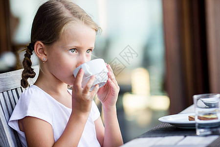 在户外咖啡厅喝可可的小女孩图片