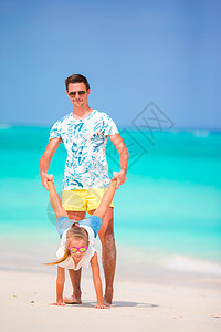 女孩和年轻父亲在热带沙滩度假期间玩得开心快乐微笑喜悦海洋成人海滩孩子婴儿情调假期图片