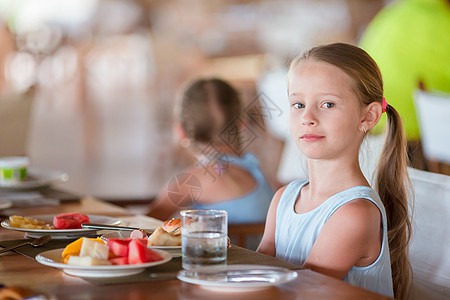 可爱的小女孩在户外咖啡厅吃早餐杯子橙子西瓜咖啡店女孩眼睛女儿餐厅稀饭桌子图片