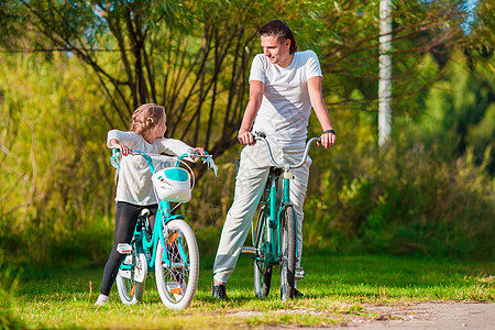 陪父母年幼的父亲和小女孩在夏暖日骑自行车男人爸爸孩子父母森林运动娱乐乐趣农村姐姐背景