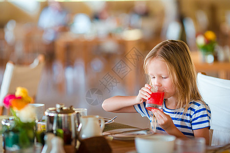 喝西瓜汁女孩小小孩在户外咖啡馆吃早饭 可爱的女孩喝新鲜西瓜汁享受早餐的滋味背景