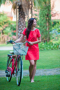 在热带度假村户外骑自行车的年轻快乐妇女图片