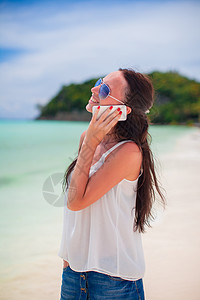 海滩上的年轻美女 用电话聊天的女青年手机女性漫游异国微笑热带细胞女孩假期享受图片