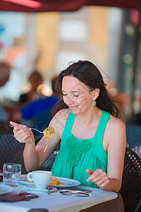 年轻妇女在意大利度假时在户外咖啡馆吃意面女士餐厅蔬菜成人旅行桌子甜点女性羊角咖啡店图片