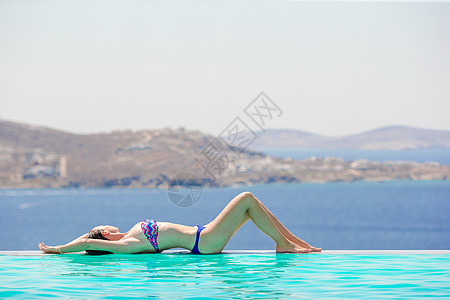 快乐的女孩在游泳池边缘放松 在希腊Mykonos的景色令人惊叹图片