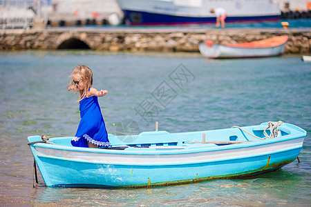 在希腊Mykonos附近海滨的蓝船小姑娘 小孩喜欢在小船上游泳图片