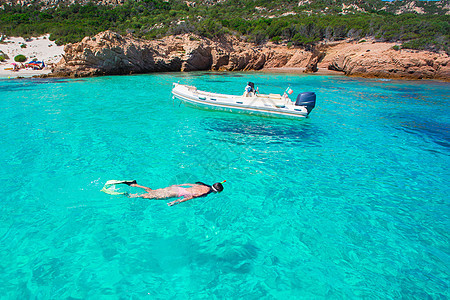 青年妇女度假时在热带水中潜伏游客面具旅行游泳巨石蓝色娱乐爱好海岸异国图片