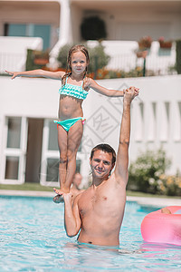 母亲和小女儿的家庭在豪华游泳池中享受暑期假期幸福娱乐男人孩子热带日光浴乐趣女孩父亲黑发背景图片