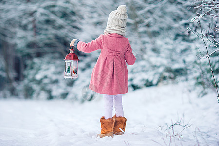 冬天带手电筒和蜡烛的可爱小女孩雪花童年闲暇喜悦展示围巾享受降雪森林新年图片