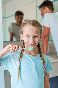 长着白牙的小漂亮女孩 和她的年轻父亲在浴室里刷牙的卫生微笑青少年幸福乐趣瞳孔孩子童年牙齿酒店图片