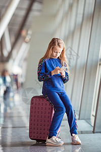 机场上可爱的小女孩 在大窗户旁边玩手机的小姑娘们图片