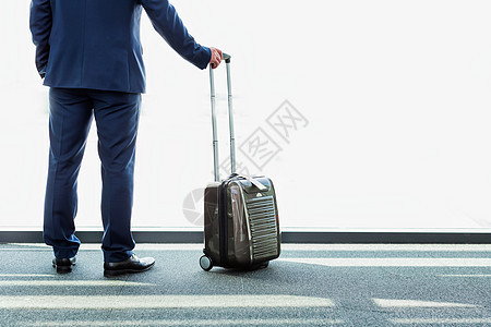 成年商务人士的肖像 他站在手提箱旁边 看着机场窗户窗外 在机场习俗手提商业飞机场企业家人士商务男人行李会议图片