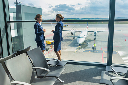 有吸引力的年轻机场工作人员在机场休息时站着说话 站立图片