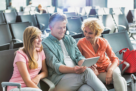 成年男子使用数字平板电脑 妻子和女儿在机场看病玩具熊时间乘客椅子童年男人国际孩子飞行手提箱图片