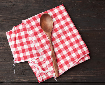 棕色木背上的木勺和红色纺织厨房毛巾图片