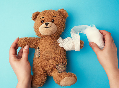 棕色的棕色卷发泰迪熊 用白色的双脚抚摸乐趣工作室蓝色损害童年儿科毛皮娃娃悲伤绷带图片
