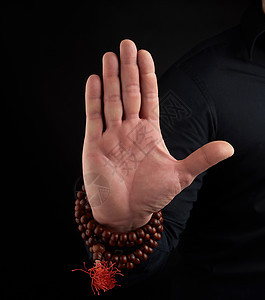 一只成年男子的手在黑暗背景上展示泥巴拳头祷告念珠身体宗教精神手腕姿势咒语瑜伽图片