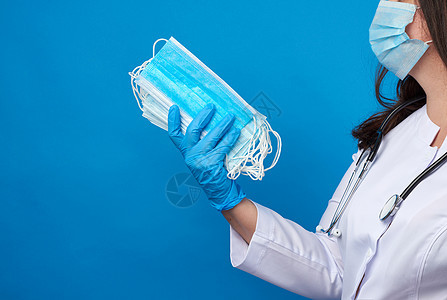 身穿白大衣和面具的医生拿着一堆防护药片女性专家保健外科蓝色实验室疾病诊所医师注射器图片