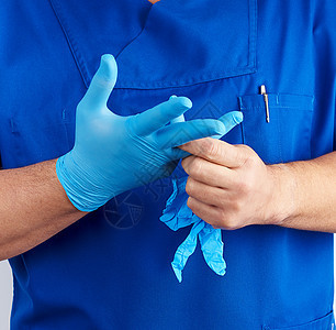 穿蓝制服的成年男医生 将蓝色不育手术套在手上图片