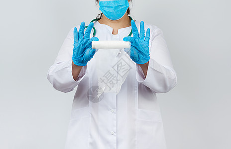穿着白外套和面罩的药服妇女拿着扭曲的纱布绷带蓝色药品保健创伤拇指医院伤口手指治疗保险图片